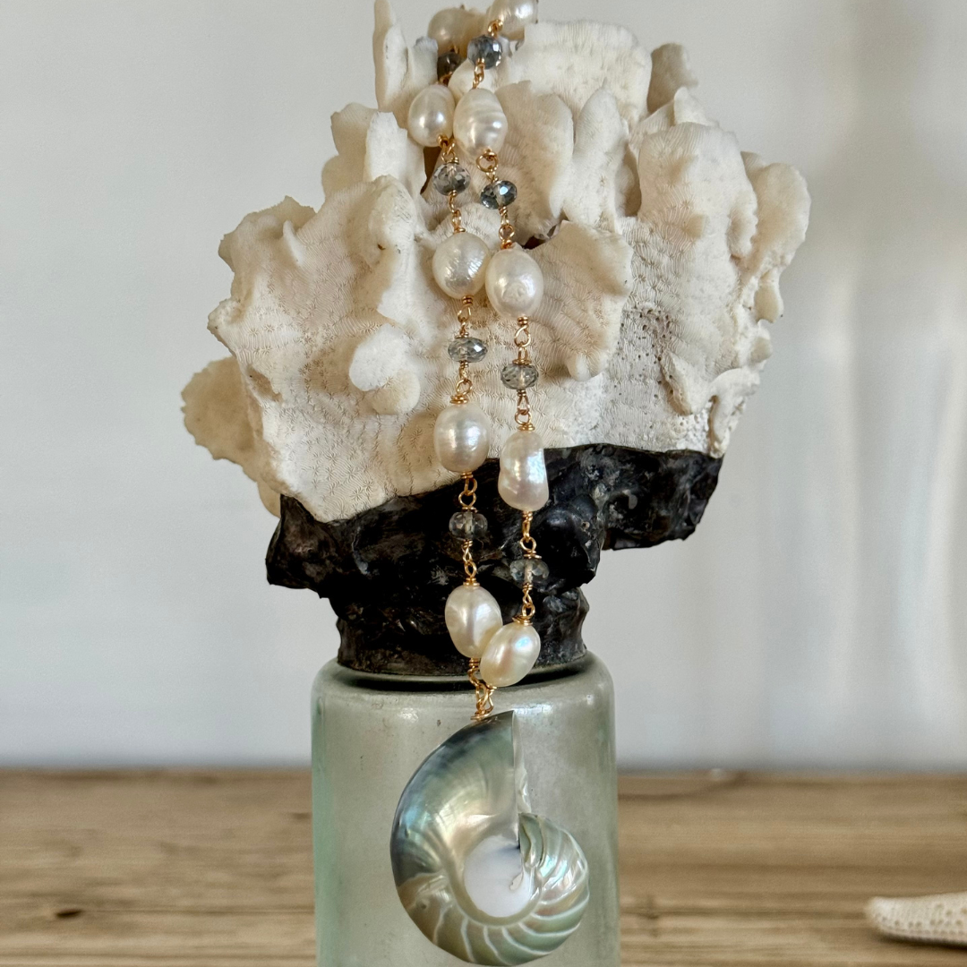 Genuine blue nautilus shell pendant draped over coral jar display. Freshwater pearls and mystic topaz accents between 14k gold-filled wire and chain.