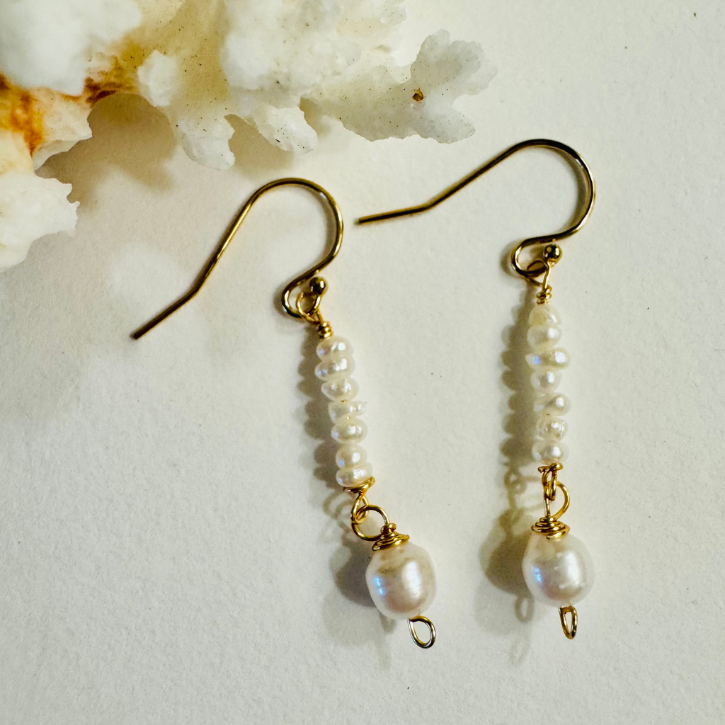 Pearl earrings with gold hooks on a light background