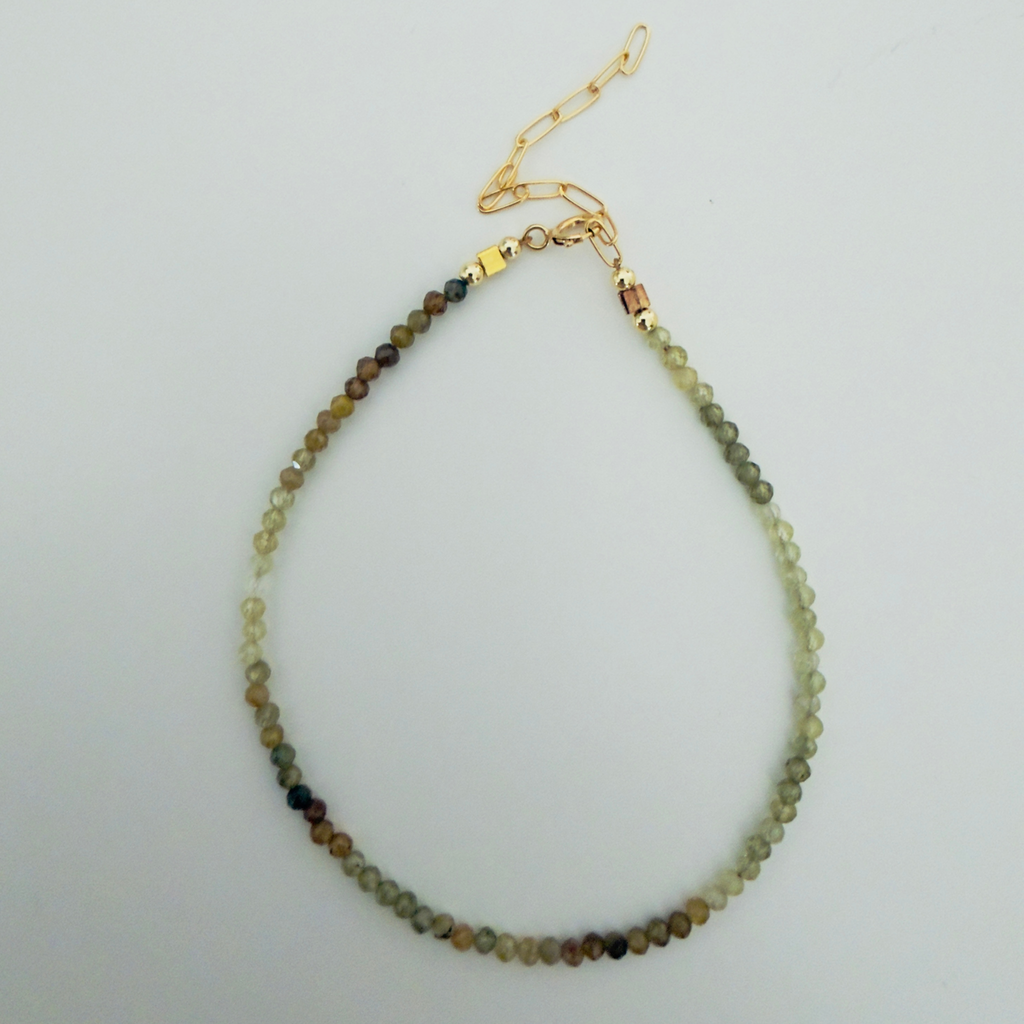 Bracelet with multicolored garnet beads on a light gray background