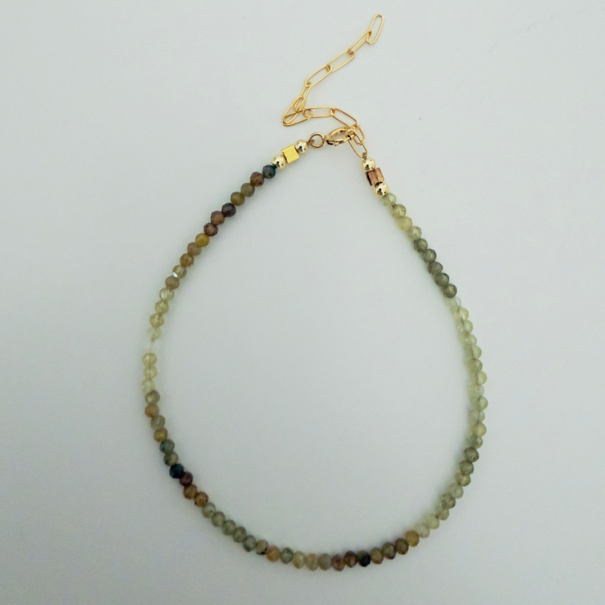 Bracelet with multicolored garnet beads on a light gray background