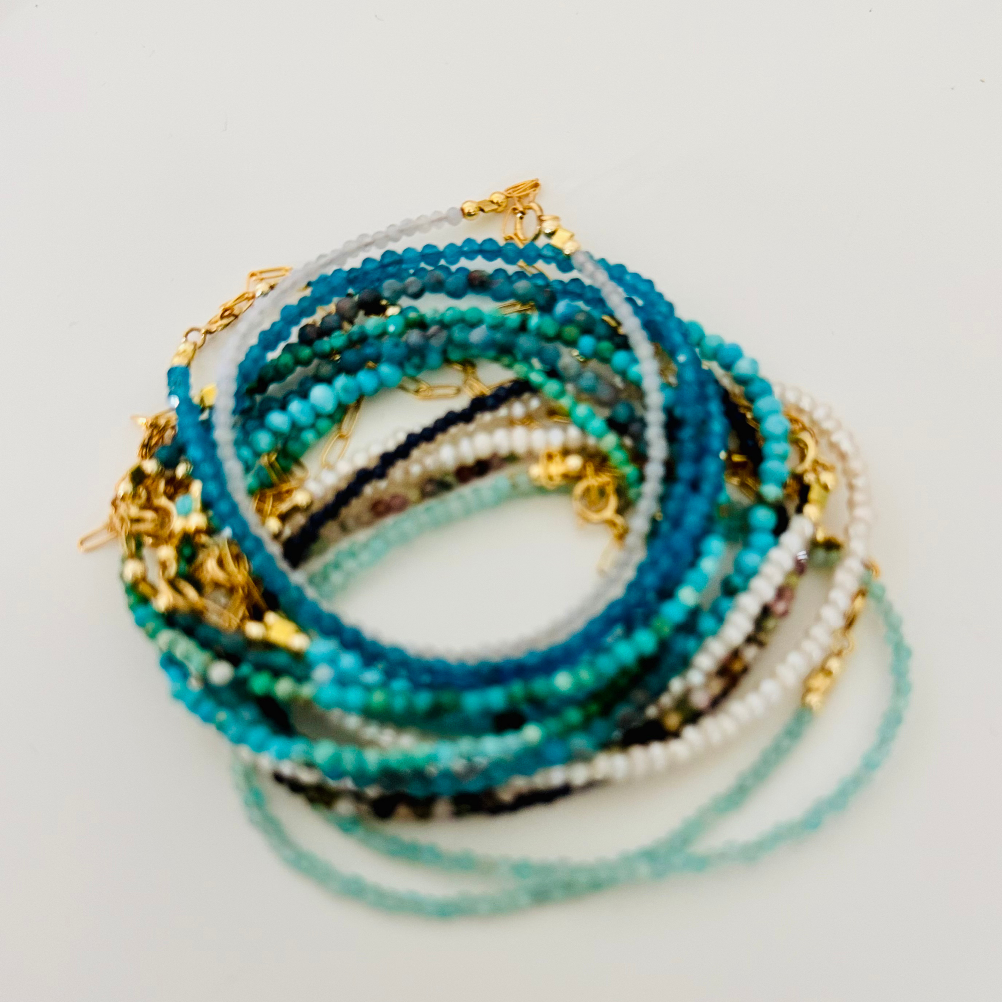 Stack of beaded bracelets with gold accents on a light background