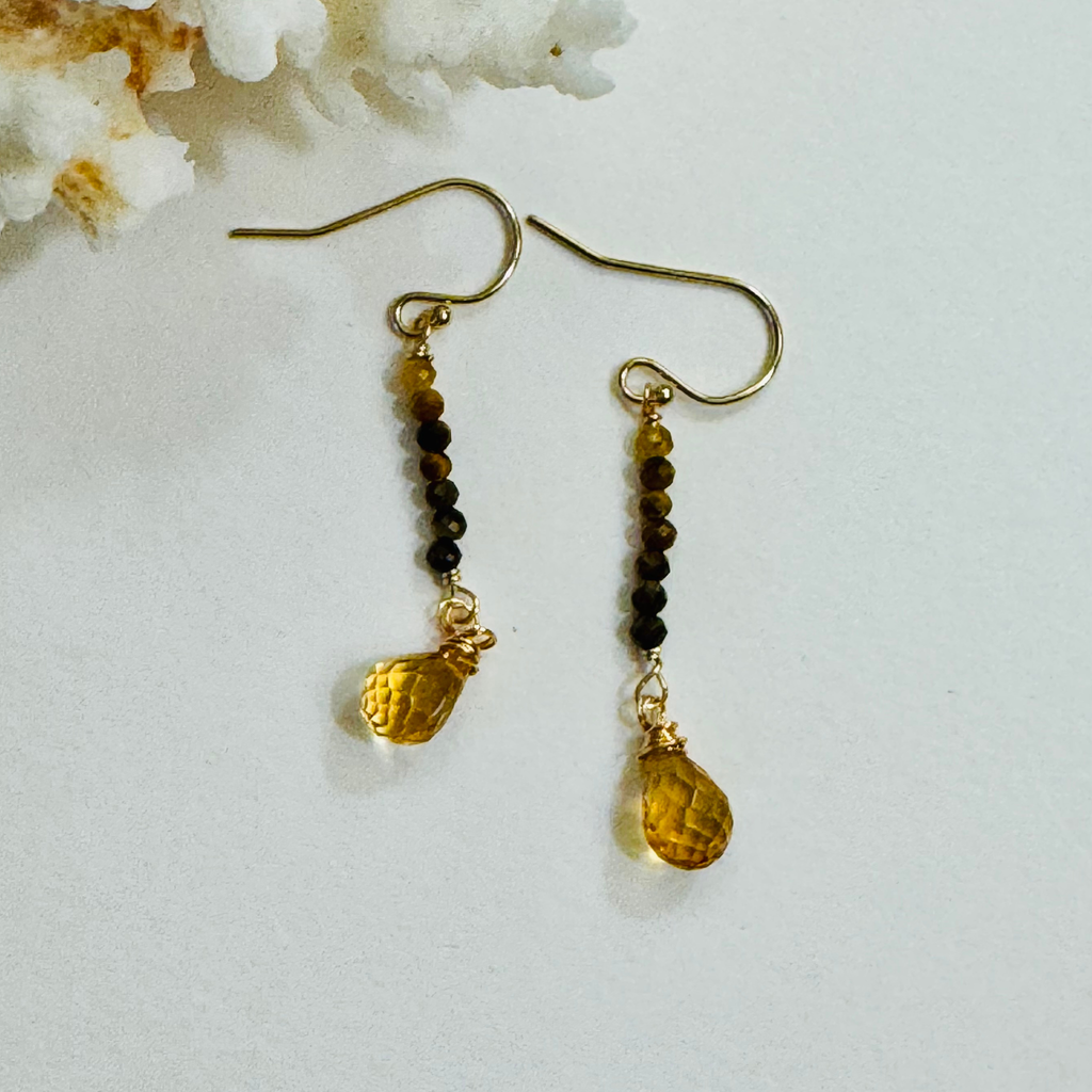 Genuine tiger eye and citrine gemstones in yellow and brown hues on 14k gold filled drop strand earrings displayed against a white background framed by white coral.