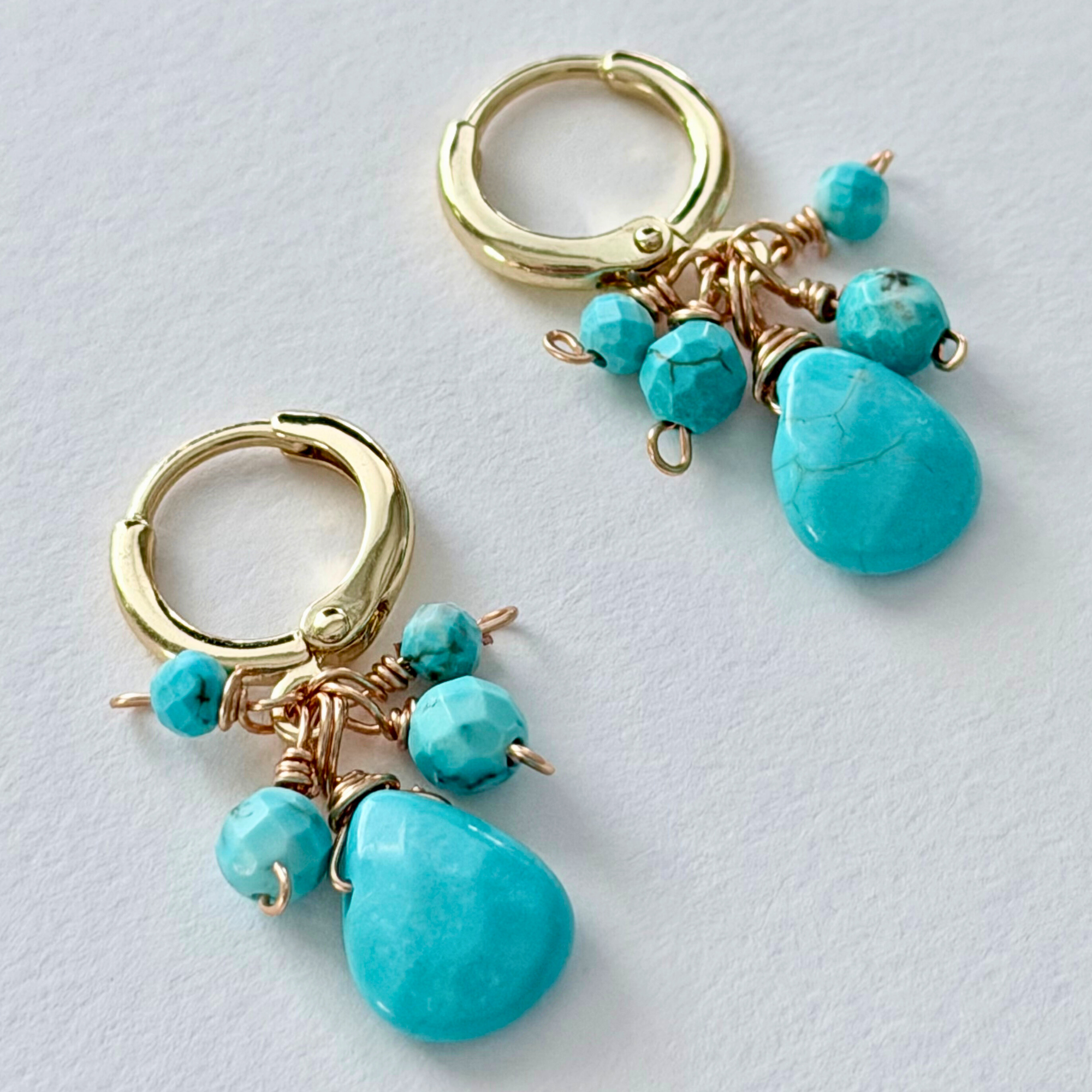 Turquoise huggie earrings on white background 